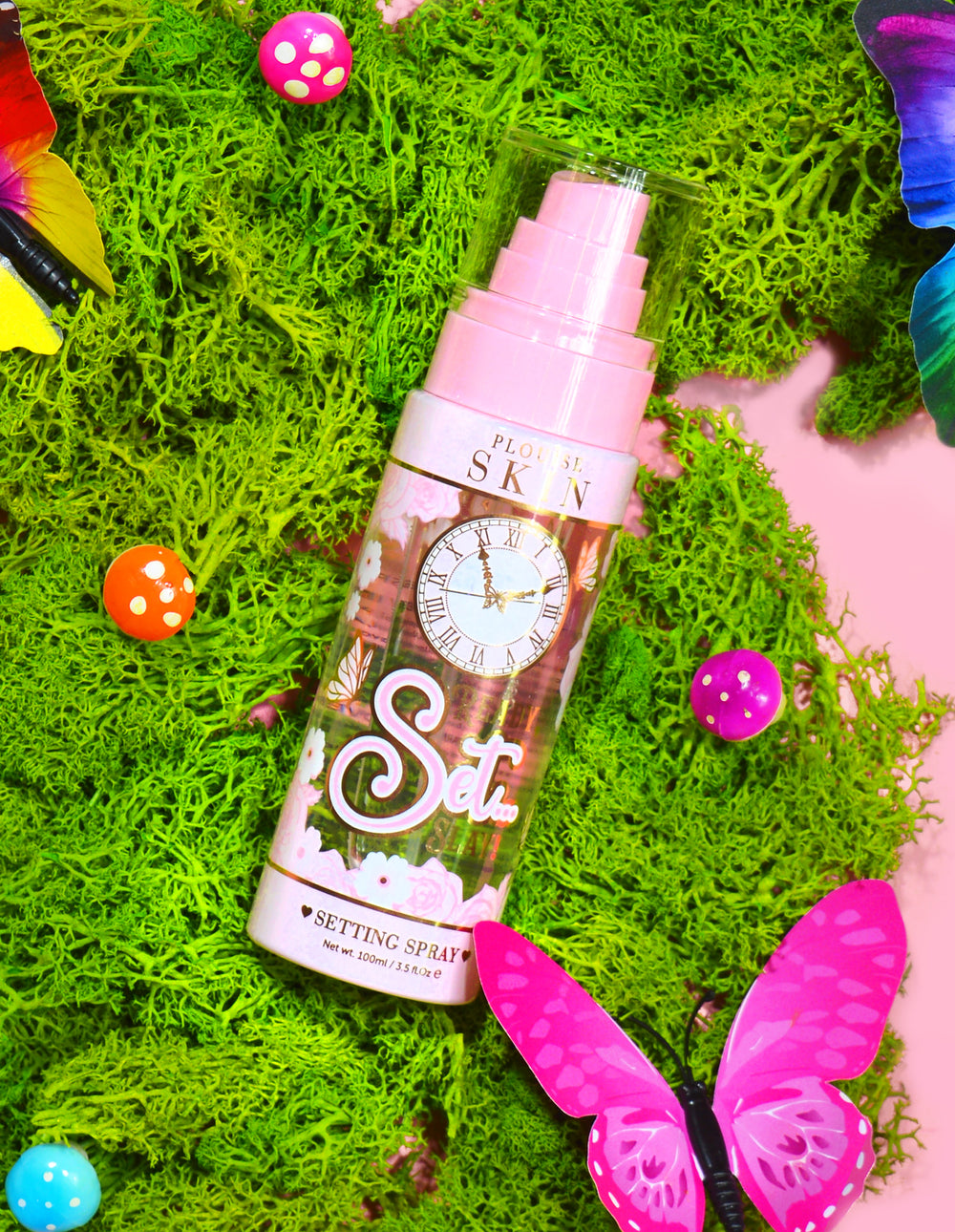 ขวดสเปรย์ P. Louise Ready Set Slay Long Lasting Setting ล้อมรอบด้วยองค์ประกอบตกแต่ง เช่น มอสเทียม ผีเสื้อ และเห็ดหลากสีสัน