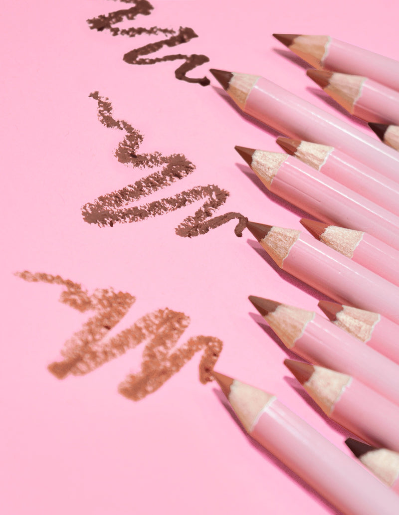 คอลเลกชันของ P.Louise ลิปไลเนอร์ที่ให้ความคมชัดสูงสุดในเฉดสีนู้ดหลากหลายเฉด วางอยู่บนพื้นหลังสีชมพูโดยมีเส้นบาง ๆ ของผลิตภัณฑ์วาดอยู่บนพื้นผิว