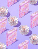คอนเทนเนอร์ใสของ P.Louise DOse of Dreams Viatmin C Capsule Face Cream โดยมีแคปซูลสีชมพูอยู่ในนั้น ล้อมรอบด้วยกล่องซีเรียลสีชมพูบนพื้นหลังสีม่วง