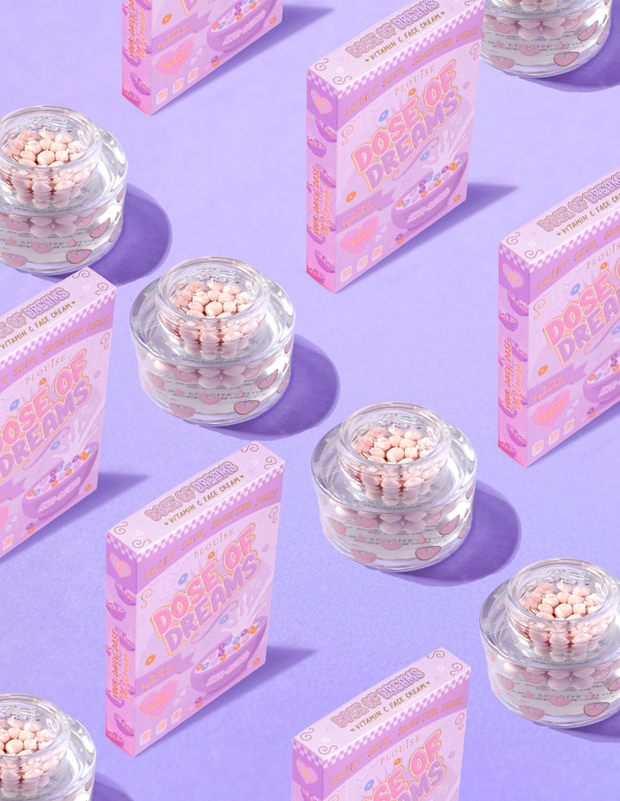 คอนเทนเนอร์ใสของ P.Louise DOse of Dreams Viatmin C Capsule Face Cream โดยมีแคปซูลสีชมพูอยู่ในนั้น ล้อมรอบด้วยกล่องซีเรียลสีชมพูบนพื้นหลังสีม่วง