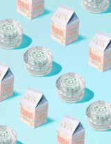 ภาชนะใสของ P.Louise Dose of Dreams Vitamin C Capsule Cream โดยมีแคปซูลสีน้ำเงินอยู่ข้างใน ล้อมรอบด้วยกล่องนม
