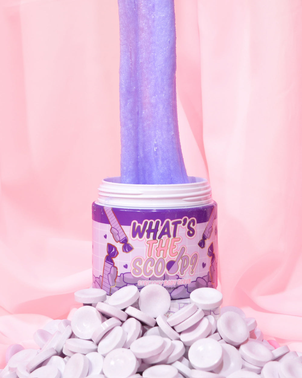 โถของ 'What's the Scoop?' สครับขัดผิวโดย P.Louise จัดแสดงด้วยขนมหวานพาร์มาไลแลคอยู่เบื้องหน้า และสครับขัดผิวถูกยืดออกจากหม้อโดยมีฉากหลังเป็นสีชมพู