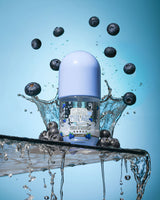 ขวดของ P. Louise Clear The Air Blueberry Gel Cleanserl ล้อมรอบด้วยบลูเบอร์รี่และละอองน้ำบนพื้นหลังสีน้ำเงิน