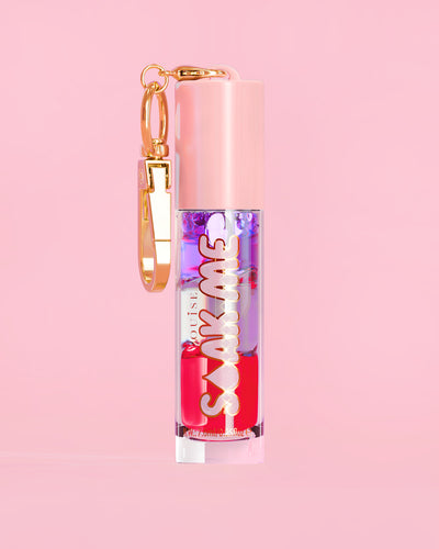 P. Louise Soak Me Lip Oil ที่มาพร้อมออยล์หลากสีสันในหลอดสีชมพู พร้อมด้วยเข็มกลัดสีทองบนพื้นหลังสีชมพู